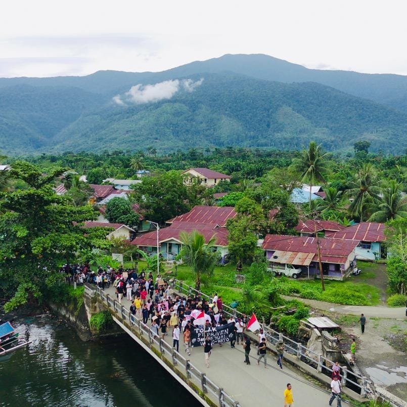 Warga berjalan bersama melintasi jembatan di Buli dengan latar Pegunungan Wato-Wato