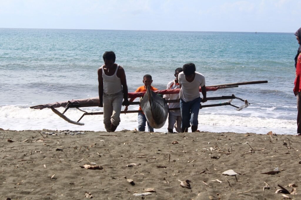 Warga pesisir bersama-sama mengangkat perahu katir dari laut ke pantai